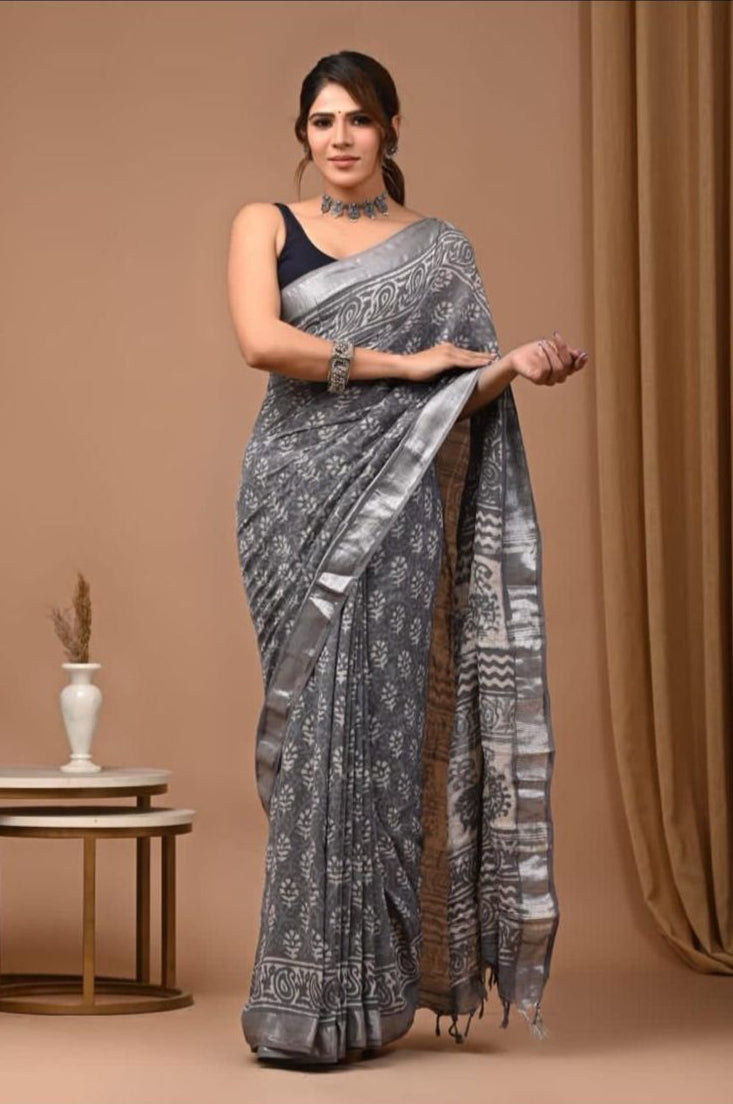 Woman wearing a gray saree with a pattern against a brown background